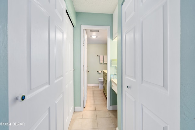 corridor featuring a textured ceiling and light tile patterned flooring