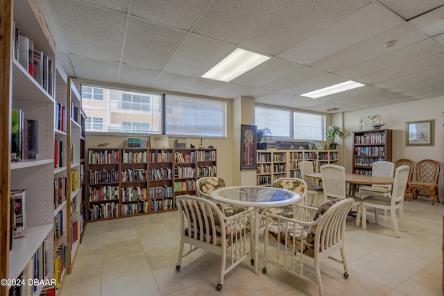 tiled dining room with a paneled ceiling and a healthy amount of sunlight