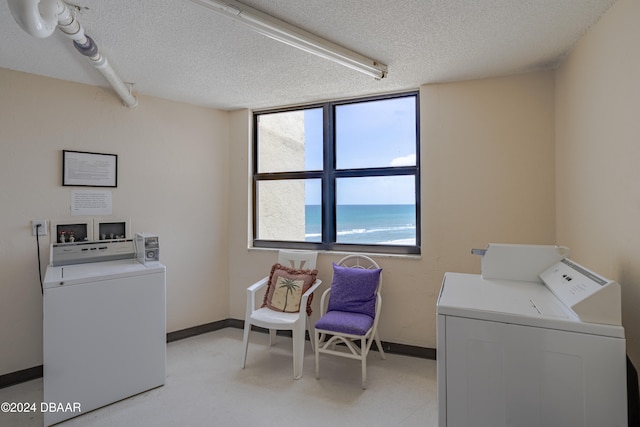 laundry area with separate washer and dryer, a water view, and a textured ceiling