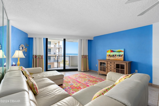 tiled living room with ceiling fan and a textured ceiling