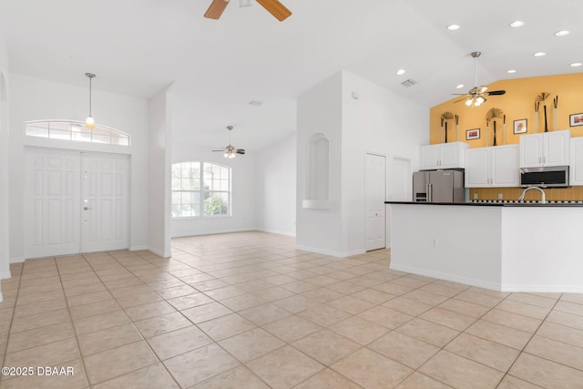 kitchen featuring ceiling fan, stainless steel appliances, high vaulted ceiling, dark countertops, and light tile patterned floors
