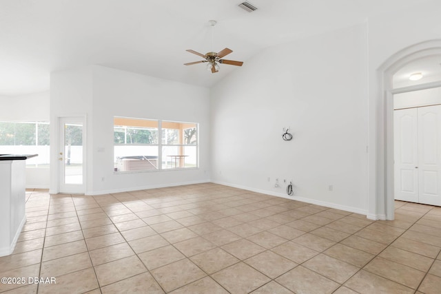 unfurnished living room with light tile patterned floors, healthy amount of natural light, a ceiling fan, high vaulted ceiling, and baseboards