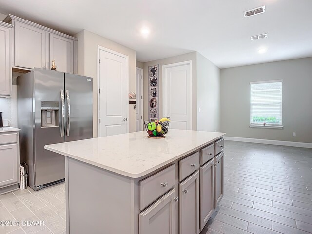 4155 Clifden Dr, Ormond Beach, FL 32174 - kitchen featuring light stone countertops, stainless steel fridge with ice dispenser, light wood-type flooring, and a kitchen island