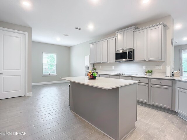 kitchen featuring electric stovetop, light wood-type flooring, a center island, and gray cabinetry