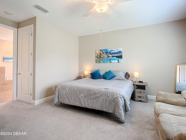 bedroom featuring light colored carpet, ceiling fan, and ensuite bath