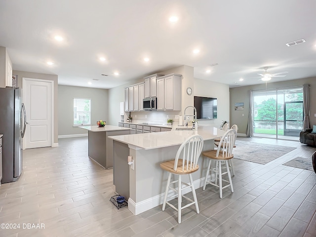 kitchen featuring appliances with stainless steel finishes, a wealth of natural light, a kitchen bar, and kitchen peninsula