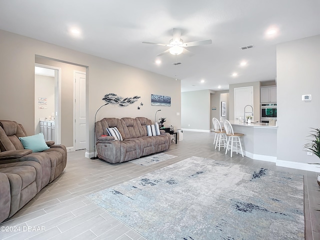 living room with light wood-type flooring and ceiling fan