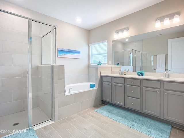 bathroom featuring wood-type flooring, vanity, and separate shower and tub