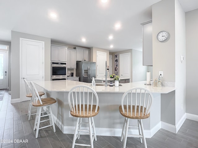 kitchen featuring kitchen peninsula, appliances with stainless steel finishes, dark wood-type flooring, and a breakfast bar area