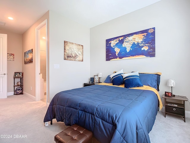 bedroom with ensuite bathroom and light colored carpet