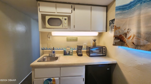 kitchen with white cabinets, fridge, and sink