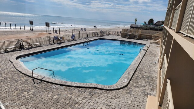 view of swimming pool with a water view and a view of the beach