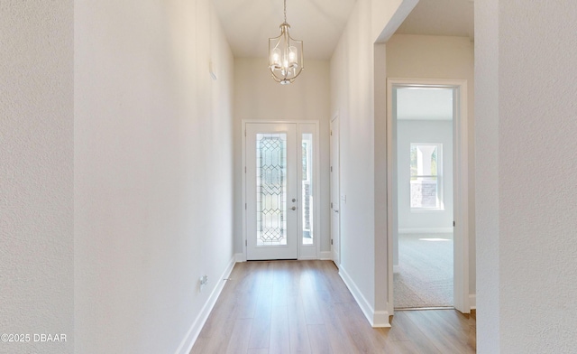 entrance foyer with a wealth of natural light, an inviting chandelier, and light wood-type flooring