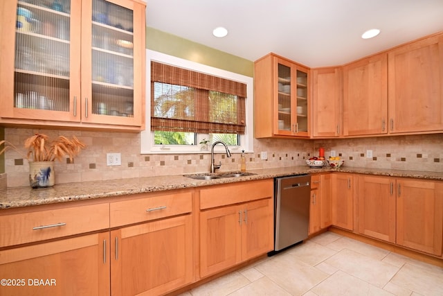 kitchen featuring sink, stainless steel dishwasher, backsplash, and light stone countertops