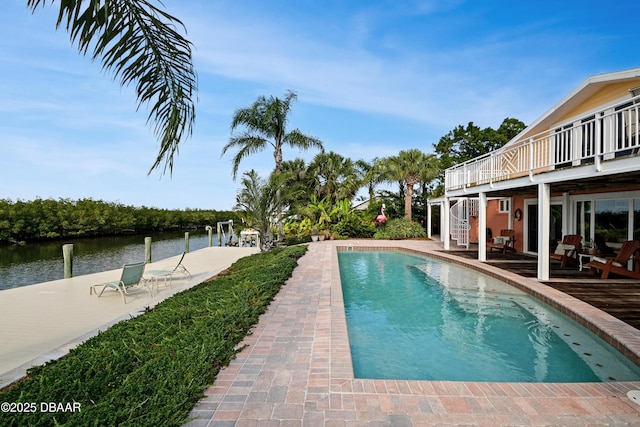 view of swimming pool featuring a patio area, a boat dock, and a deck with water view