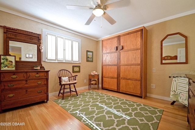 sitting room featuring light wood-type flooring, ceiling fan, and crown molding