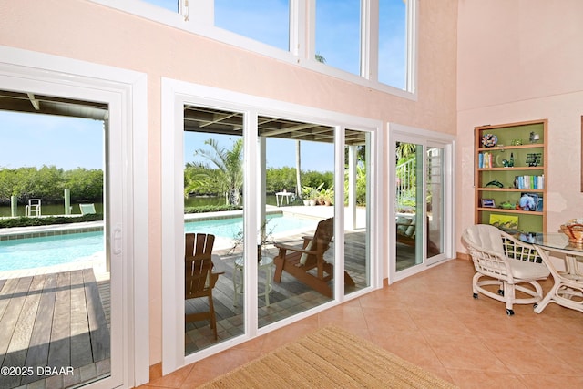 entryway with a high ceiling, a healthy amount of sunlight, and light tile patterned floors