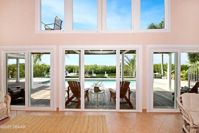 doorway to outside with a towering ceiling and tile patterned floors