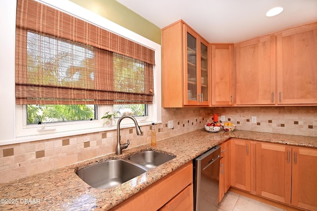 kitchen with light stone countertops, stainless steel dishwasher, light tile patterned floors, decorative backsplash, and sink