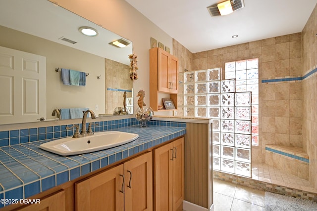 bathroom featuring vanity, tile patterned flooring, tasteful backsplash, and tiled shower