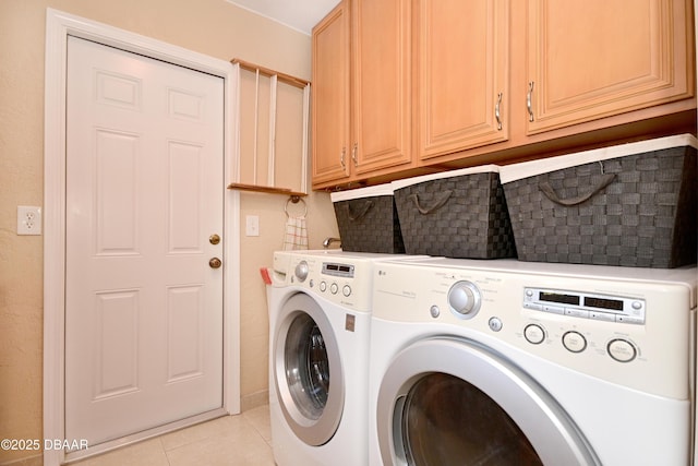 clothes washing area with cabinets, washer and clothes dryer, and light tile patterned floors