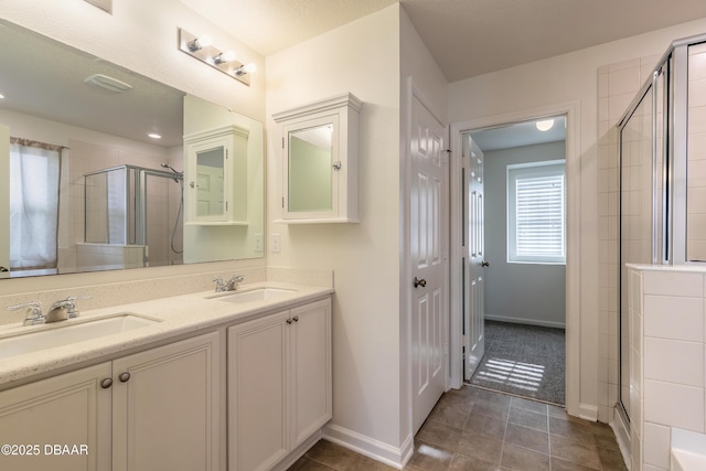 full bath featuring tile patterned floors, a sink, a shower stall, and double vanity