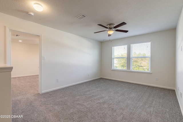 carpeted empty room featuring a textured ceiling, ceiling fan, visible vents, and baseboards