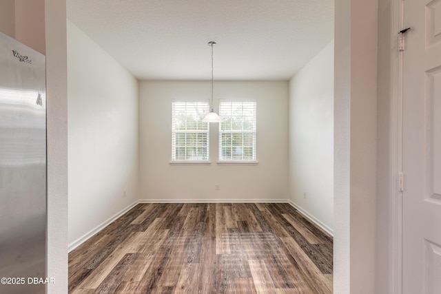 unfurnished dining area with baseboards and dark wood-style flooring