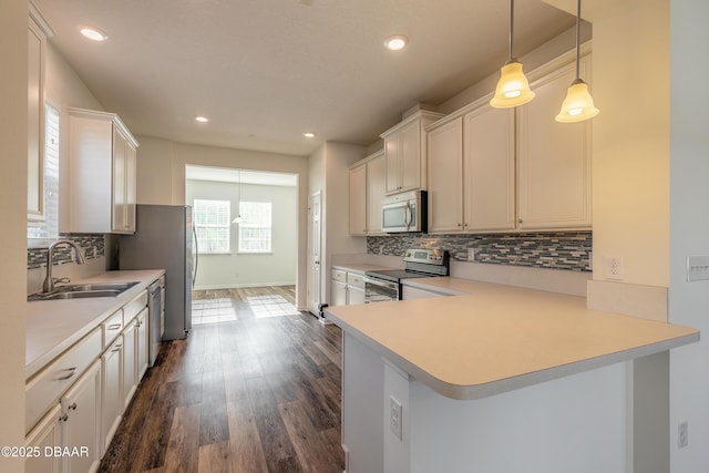 kitchen with light countertops, backsplash, appliances with stainless steel finishes, dark wood-type flooring, and a sink