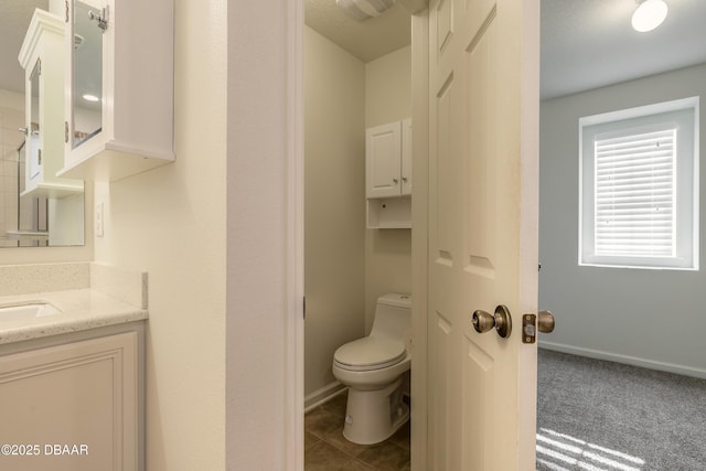 bathroom with tile patterned flooring, baseboards, vanity, and toilet