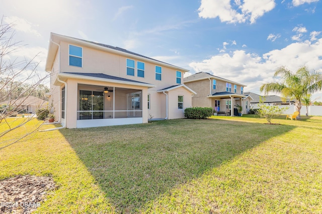 back of property featuring a ceiling fan, a sunroom, a lawn, and stucco siding