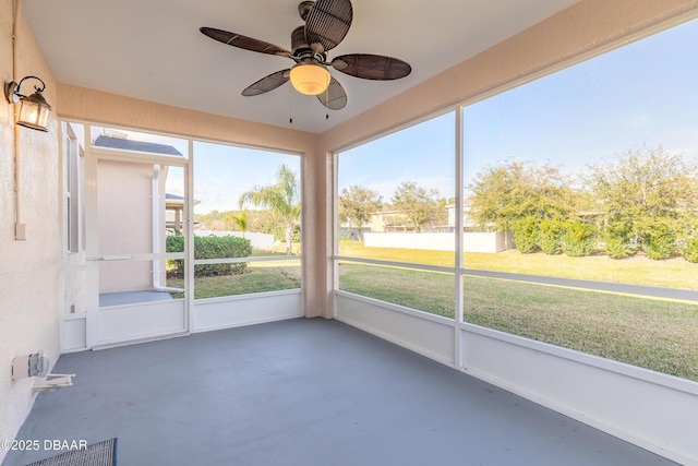 unfurnished sunroom featuring a ceiling fan and a wealth of natural light