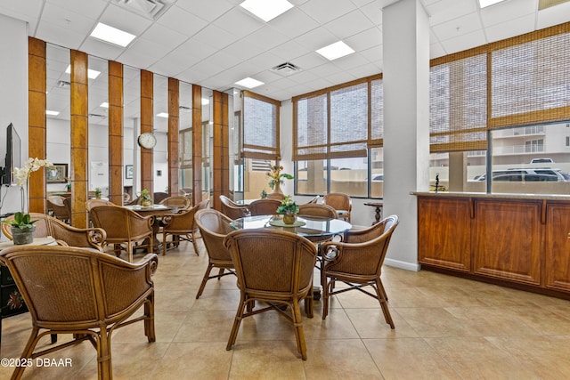 dining space featuring light tile patterned floors and a drop ceiling