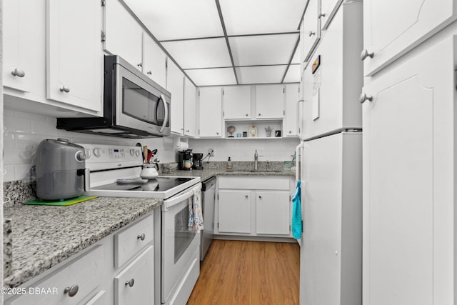 kitchen with white cabinetry, stainless steel appliances, sink, and light hardwood / wood-style flooring