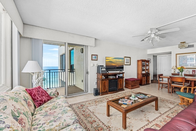 living room with light tile patterned floors, a textured ceiling, and ceiling fan