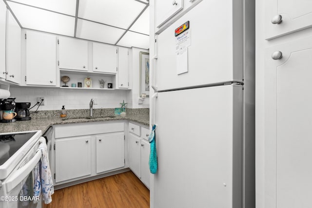 kitchen featuring white cabinetry, sink, decorative backsplash, white appliances, and light wood-type flooring