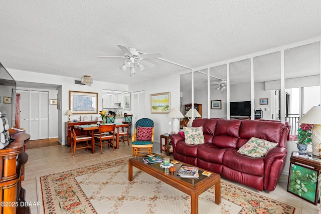 tiled living room with ceiling fan and a textured ceiling