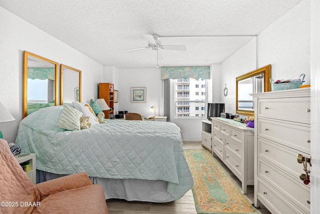 bedroom with ceiling fan, light hardwood / wood-style flooring, and a textured ceiling