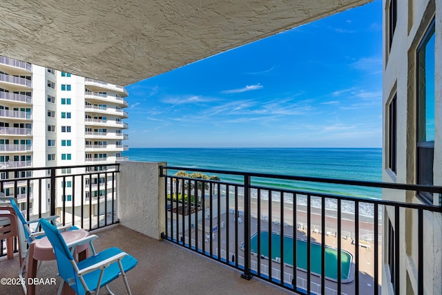 balcony featuring a view of the beach and a water view