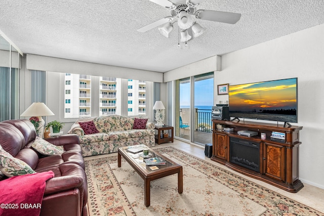 living room featuring light tile patterned floors, a textured ceiling, and ceiling fan