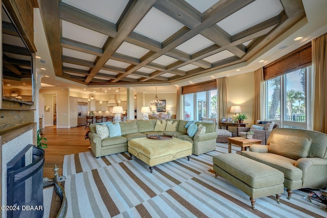 living room with beamed ceiling, a notable chandelier, light hardwood / wood-style flooring, and coffered ceiling