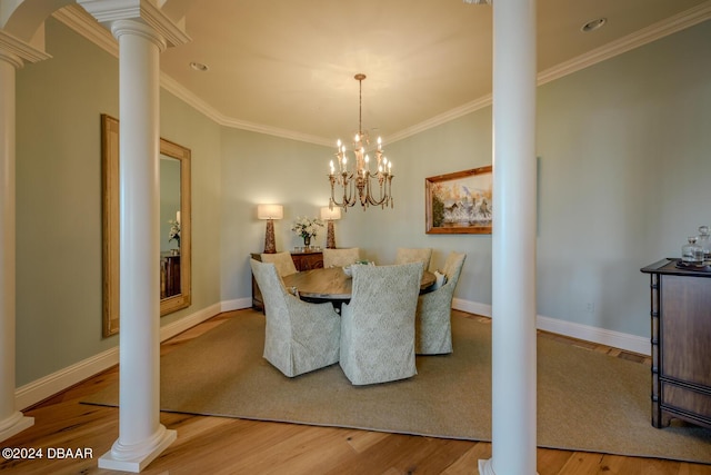 dining area featuring ornate columns, ornamental molding, a chandelier, and light hardwood / wood-style floors