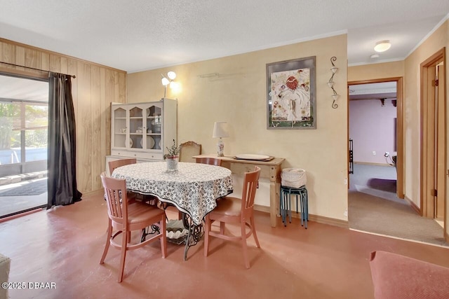 5967 Plantera Ct, Port Orange, FL 32127 - dining space featuring ornamental molding, a textured ceiling, finished concrete flooring, baseboards, and wood walls