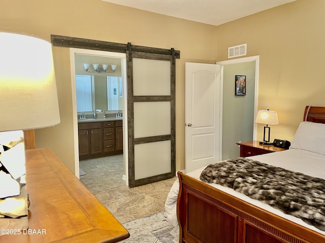 bedroom featuring ensuite bathroom and a barn door