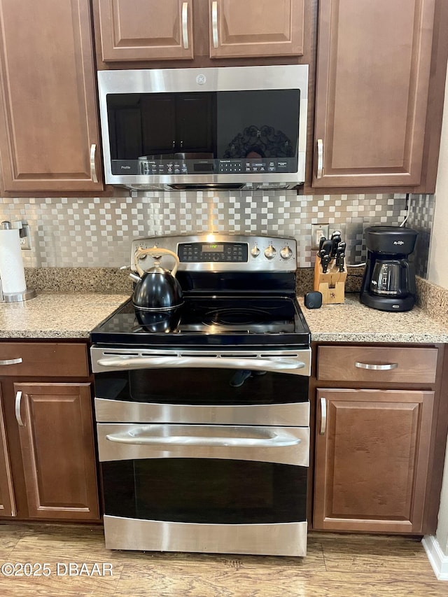 kitchen featuring appliances with stainless steel finishes, light stone countertops, and backsplash