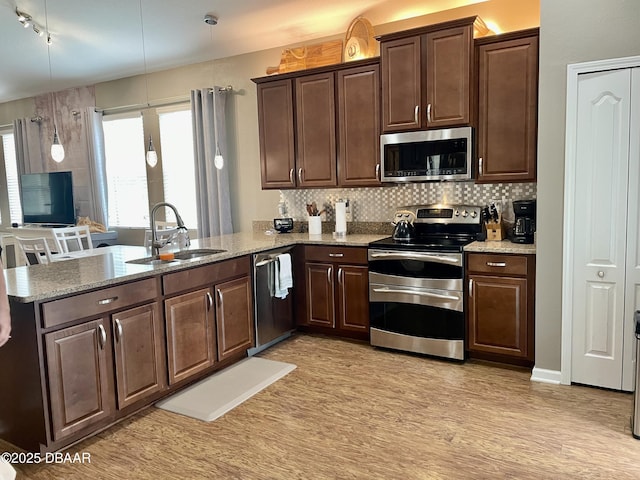 kitchen featuring sink, hanging light fixtures, stainless steel appliances, tasteful backsplash, and kitchen peninsula