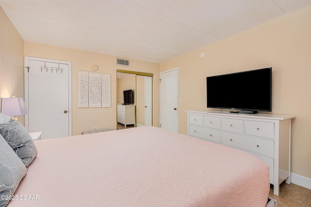 bedroom with a textured ceiling, tile patterned flooring, and two closets