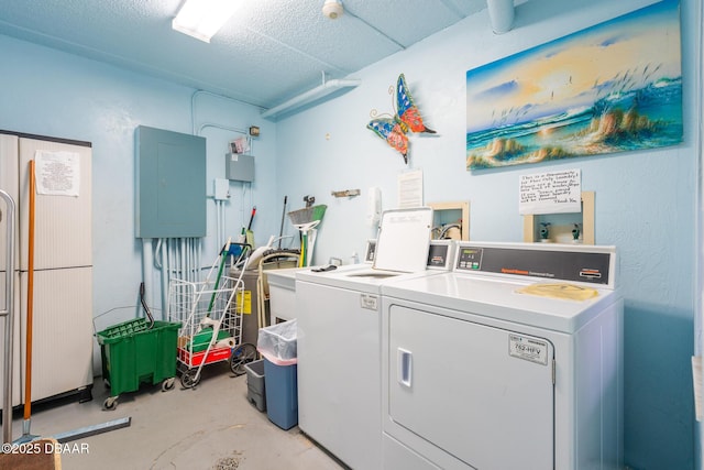 washroom with washing machine and dryer, electric panel, and a textured ceiling