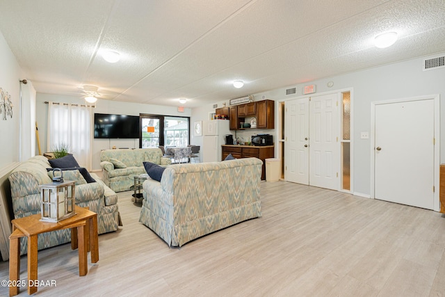 living room featuring light wood-type flooring, a textured ceiling, and ceiling fan