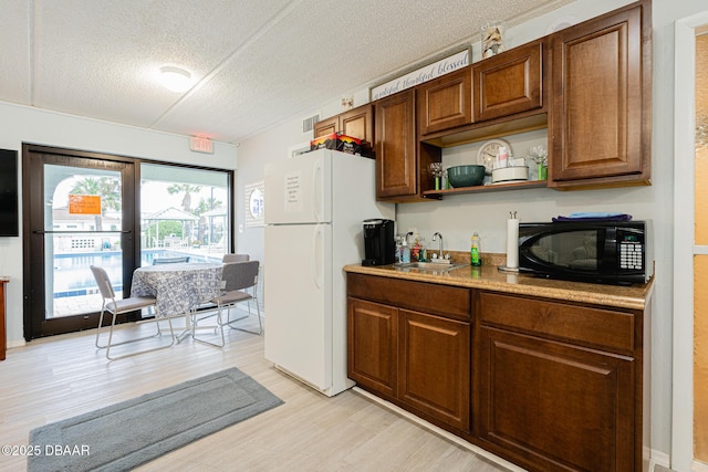 kitchen featuring light hardwood / wood-style floors, sink, a textured ceiling, and white fridge